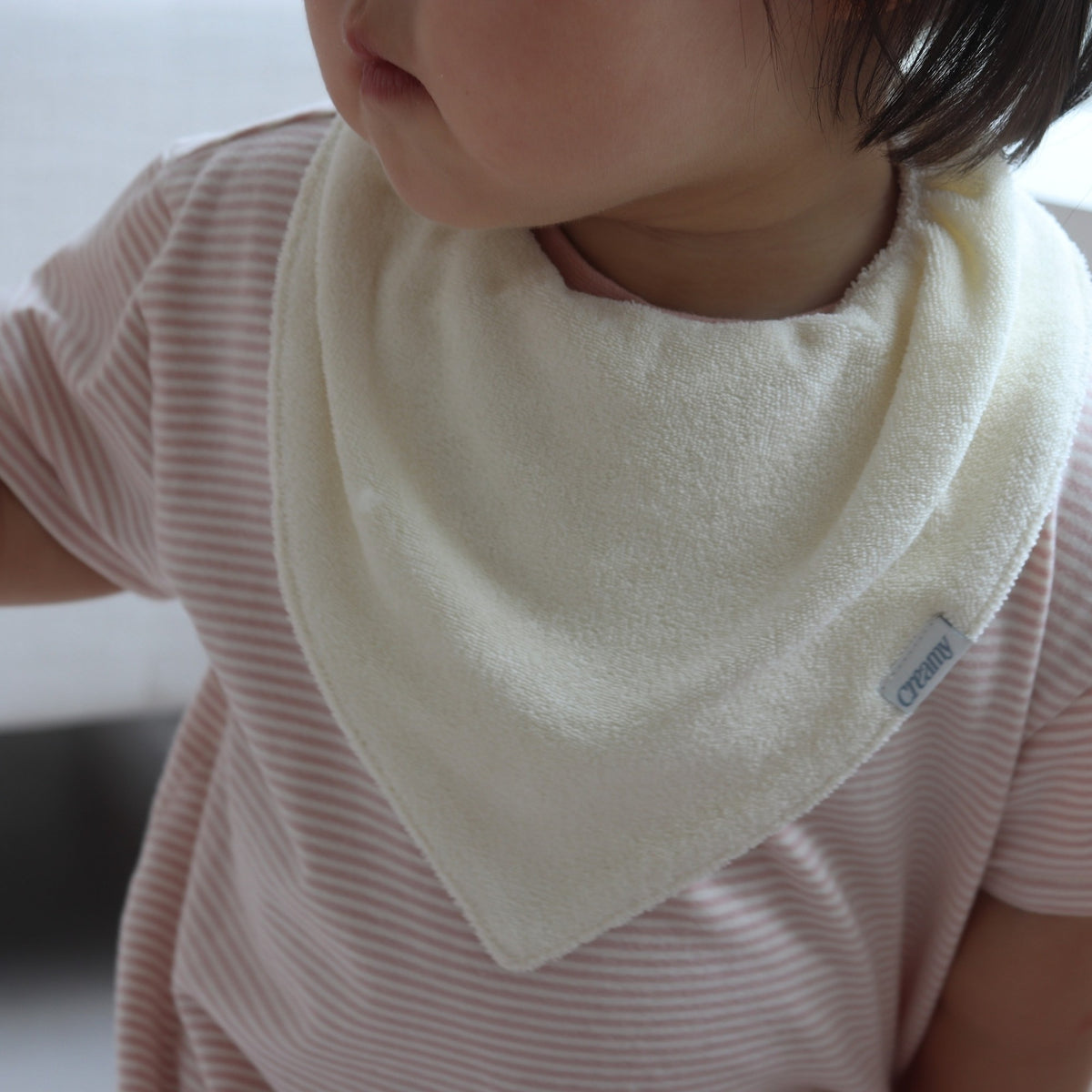 Baby wearing Creamy Gelato Bib in Vanilla